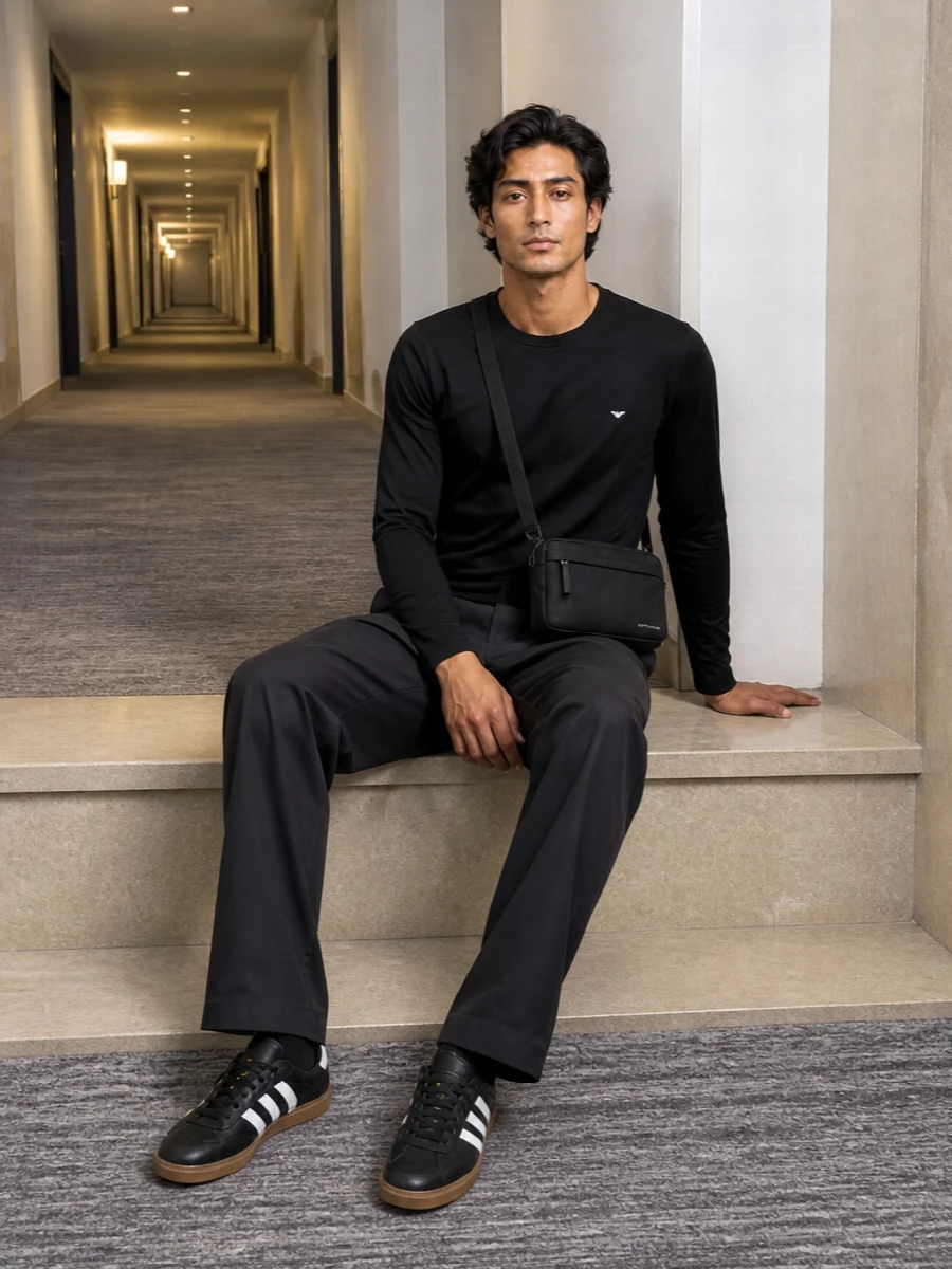 A black long-sleeve tee sits cleanly over relaxed charcoal drawstring trousers, keeping the line simple and quietly polished. Monochrome leather trainers add a low-profile sport edge, while the compact crossbody brings just enough structure for city days without breaking the minimalist mood.
