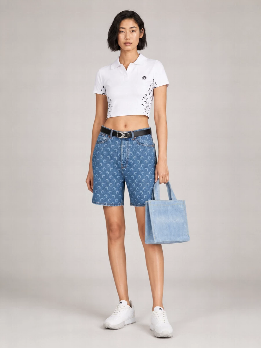 Marine Serre’s moon-print bermudas meet a cropped lunar polo and clean white runners for a sharp, athletic spin on denim. The mini faded tote keeps the palette cool and tonal, while a slim black belt structures the waist without disrupting the graphic story. It is an easy city uniform that still reads considered from every angle.