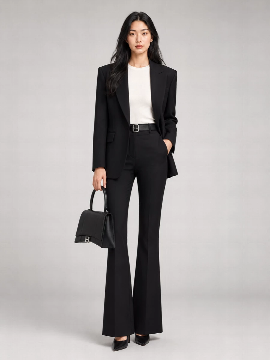 A sharp black Balenciaga blazer sits over high-rise flared tailoring for a long, graphic line that feels suited to serious meetings and after-dark reservations alike. A pointed black pump and structured top-handle keep the mood pure and precise, while a slim logo belt quietly anchors the waist and repeats the metal accents. The result is strict, modern suiting that reads confident rather than loud, all in deep black.