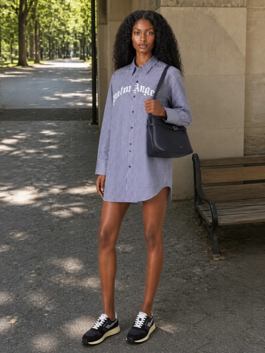 Navy Autry runners ground the Palm Angels striped shirt dress in a sporty, borrowed-from-the-boys way that still feels precise. The longline shirting and bare legs keep it easy for warm city days, while the logo chest hit chats subtly with the sneaker branding. A structured Manu Atelier navy baguette tucks under the arm for a clean, grown-up finish that offsets the streetwear energy.