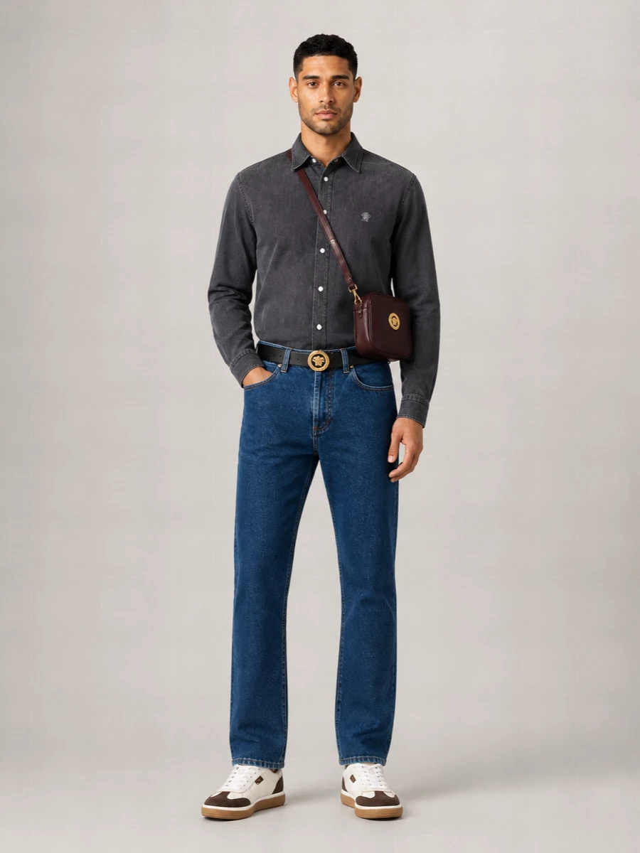 Indigo straight-leg denim meets a charcoal Versace shirt for a clean, modern take on city dressing that stays relaxed but clearly considered. Warm accents through leather and hardware tie the palette together, with white and brown sneakers and an oxblood crossbody giving the outfit a subtle yet confident edge. The result feels sharp enough for dinner yet easy for daytime, all while staying firmly in that refined Italian street-preppy space.