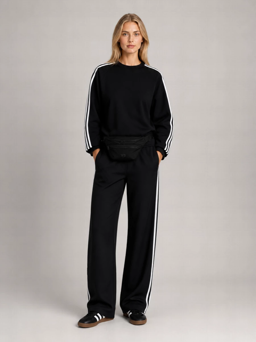 A monochrome sport set brings the Adidas slip-ons into a cleaner, more directional space, with Y-3’s boxy striped sweatshirt sitting sharp against relaxed wide-leg track pants. The repeated black and white stripes create a long, graphic line, while the belt bag keeps everything streamlined and functional for city days. Choosing separates over a dress lets the sneaker’s heritage codes run through the whole outfit rather than fighting them with a single-piece silhouette.