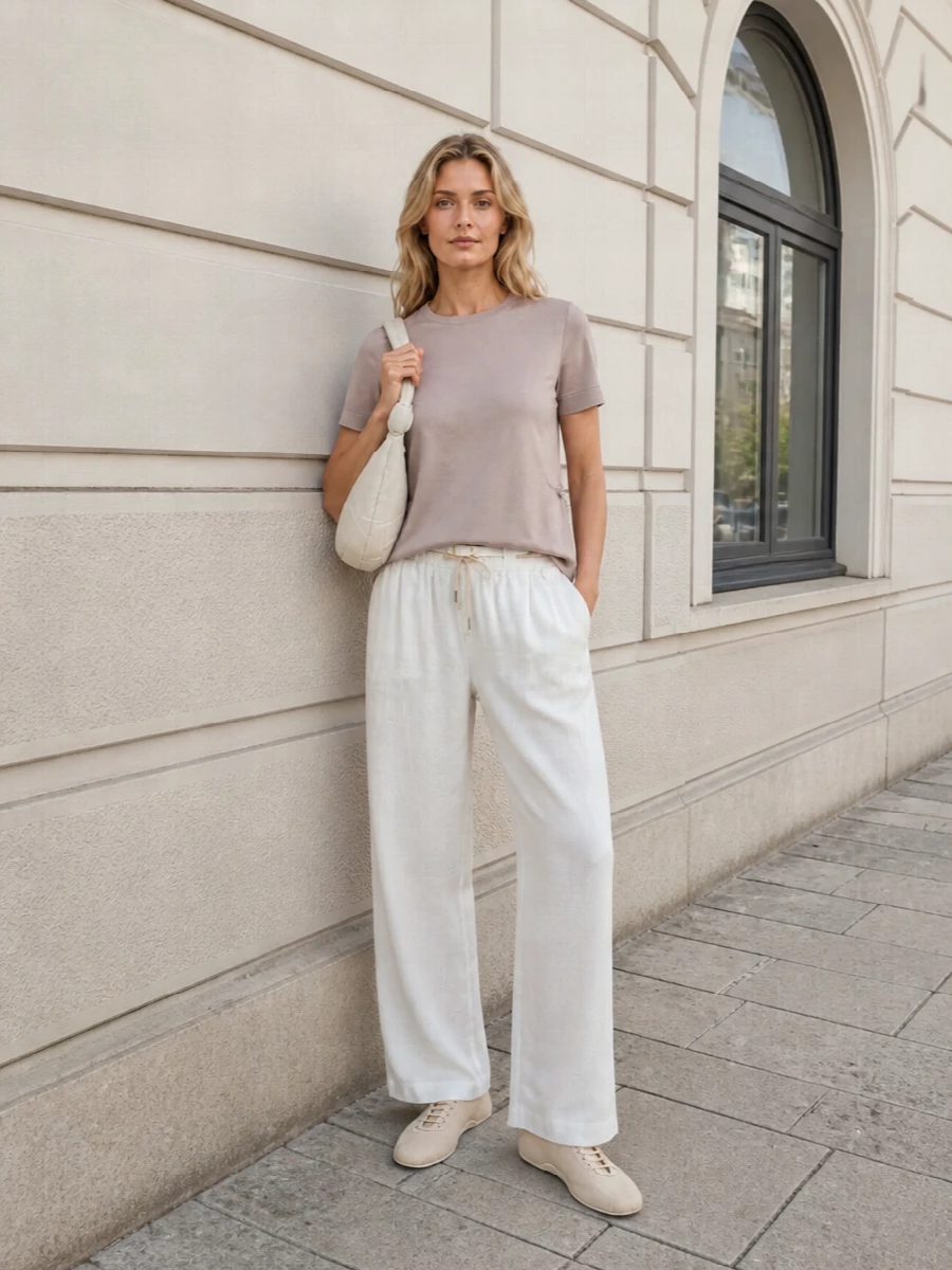 Dusty blush and soft ivory come together in a calm, tonal pairing that feels polished yet relaxed. The A-line tee floats over fluid wide-leg trousers, with the slim nude sneaker and sculpted ivory hobo keeping the mood minimal and quietly luxe. A fine white belt introduces just enough definition and gold detail without disturbing the softness of the silhouette.