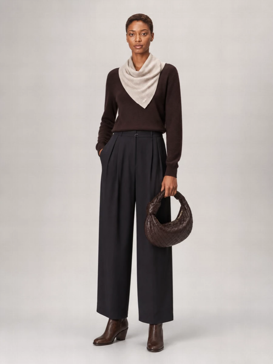 Deep chocolate and charcoal sit in quiet conversation here, with the asymmetric knit and high waisted wide-leg trouser creating a long, relaxed but considered line. The Western inflected boot grounds the volume, while the padded crescent bag and soft kerchief keep everything tactile and modern rather than severe.