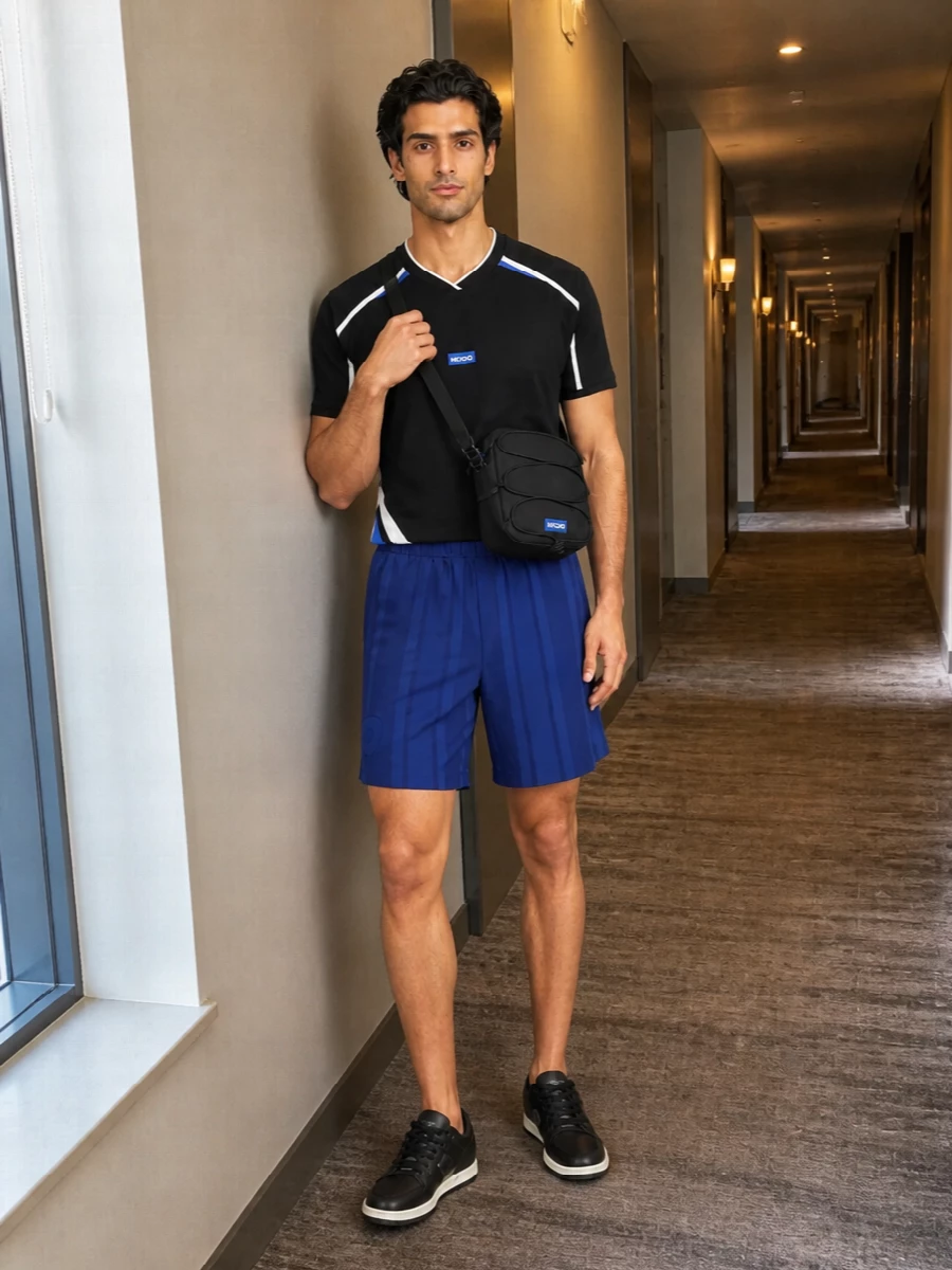 A graphic Hugo tee sits over tonal navy and cobalt BOSS shorts for a tight, sport-led palette that feels considered without going loud. Black Hugo sneakers and a compact crossbody keep the silhouette clean and agile, ideal for city days, travel or low-key nights. The result is athletic, streamlined and clearly branded without feeling busy.