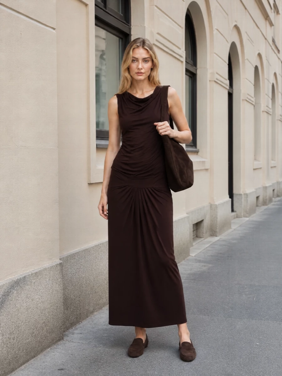 The chocolate maxi dress and Tod’s driving loafers create a long, tonal line that feels quietly refined yet easy to wear. Rich browns stay close to the body and the ground, so the silhouette reads lean rather than heavy. A dark suede shoulder tote finishes the palette in the same family of browns, keeping the whole outfit calm, modern, and city ready without extra complication.