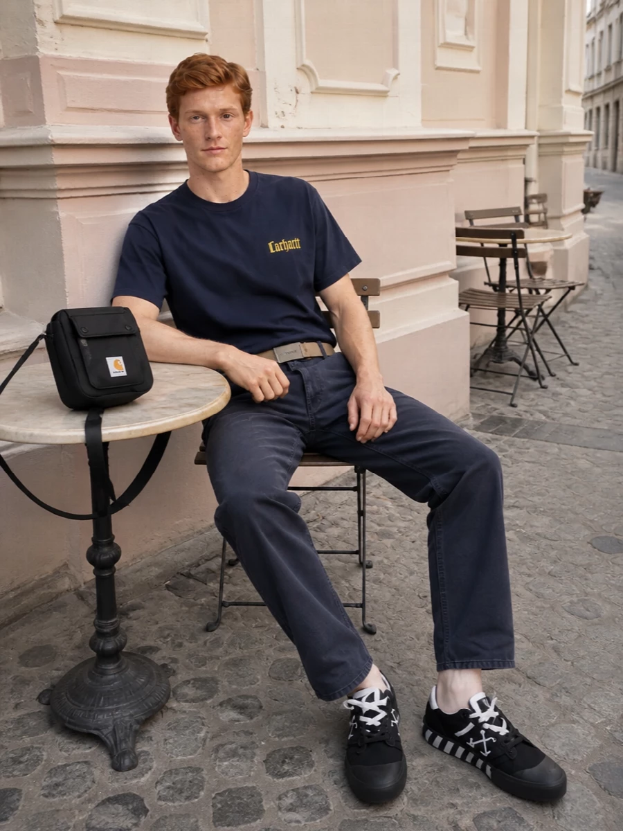 Navy on washed navy keeps this Carhartt WIP pairing tight and utilitarian, with the mustard chest hit as the only real color statement. Straight lines through the tee and pant give a clean, relaxed proportion that lets the Off-White sneakers carry the graphic punch. The small crossbody and webbing belt finish it with practical, city-ready hardware detail rather than extra noise.