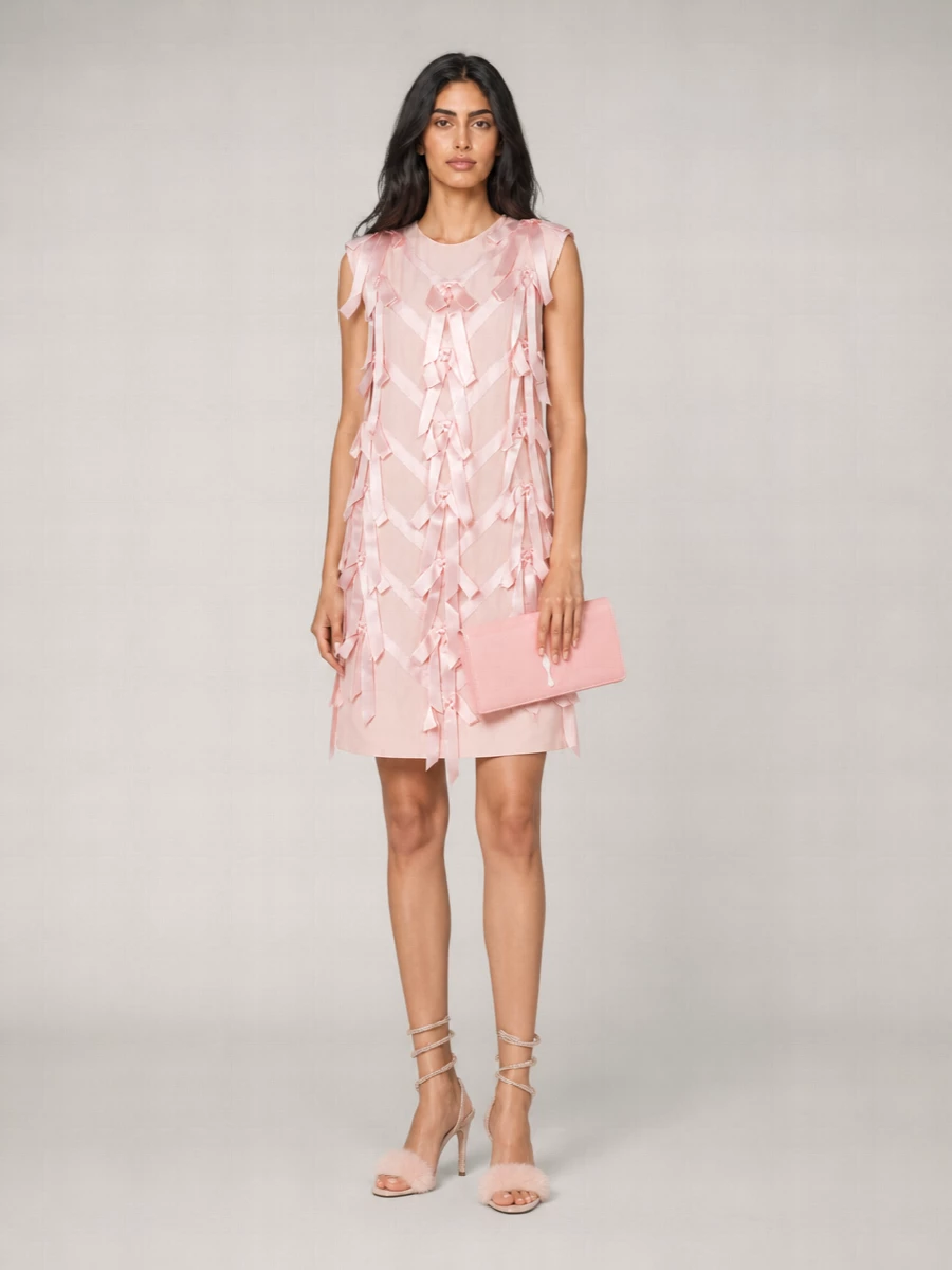 I’m building around the dress path here, because a single sculpted piece lets the Rene Caovilla sandals feel like jewelry rather than competing with separates. The blush Prada shift with structural bows echoes the shoes’ romantic, almost confectionary mood while keeping the line sleek and modern. A glossy blush clutch finishes the palette in a focused, monochrome way so the fur strap and crystal spiral can stay the star detail at your feet.