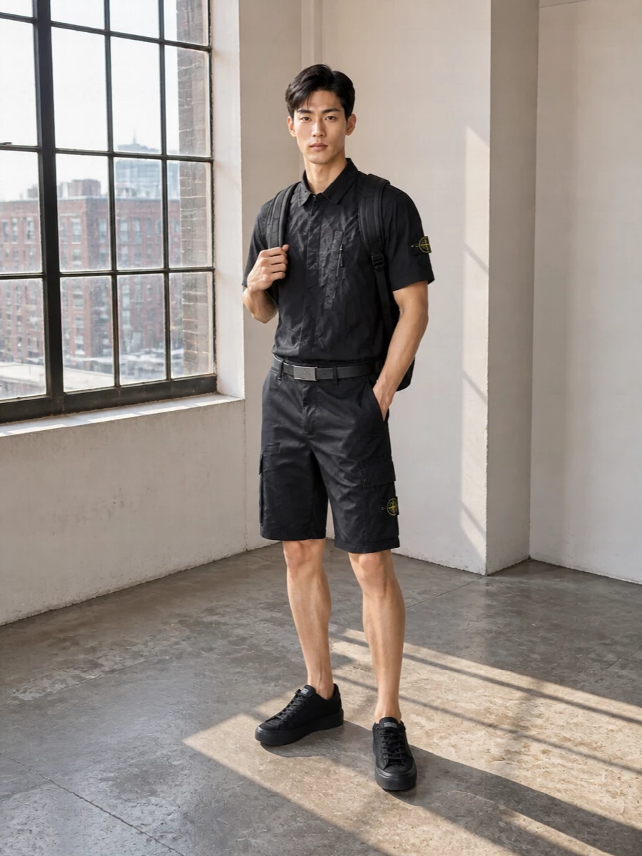 All-black Stone Island pieces keep this grounded in clean, technical streetwear, with the crinkled nylon shirt echoing the cargo detailing of the shorts. The monochrome sneakers continue the low-key utility story, while a structured backpack and slim belt add just enough polish for daily city wear without losing ease.