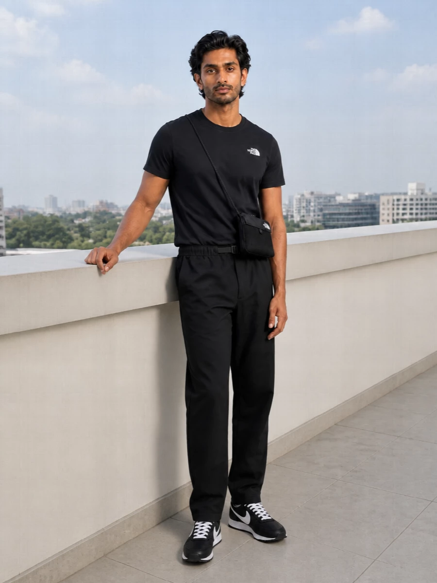 Head-to-toe black keeps this North Face outfit tight and graphic, with the logo tee and straight technical pant reading clean rather than gym-only. The retro runners bring a low-profile sport edge, while the slim crossbody adds just enough utility without disturbing the streamlined silhouette. It is an easy grab for days that move from commute to light exploring with no change required.
