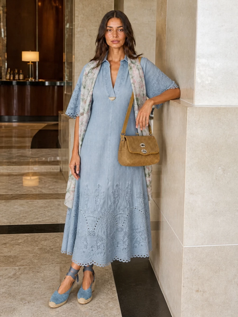 A soft chambray midi meets dusty-blue espadrille wedges for a romantic, sunlit silhouette that feels relaxed yet considered. The honey-tan woven crossbody adds structure and warmth, keeping the mood more countryside lunch than beach day. A whisper-light floral scarf finishes the palette with a gentle wash of color and movement without disturbing the dress’s broderie detail.