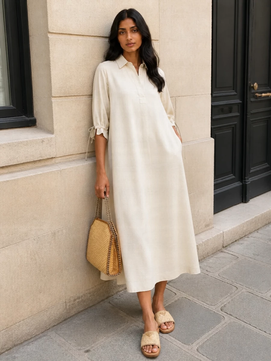 An ivory Max Mara midi shirt dress anchors the look with effortless, tailored ease that complements the bag’s woven texture and warm metal chain. The Prada raffia slides pick up the straw tones and keep the silhouette relaxed and summery, creating a cohesive quiet-luxury story that feels perfect for sunlit city days or resort lunches. Together, the neutral palette and soft structure read refined yet completely unforced around the statement tote.
