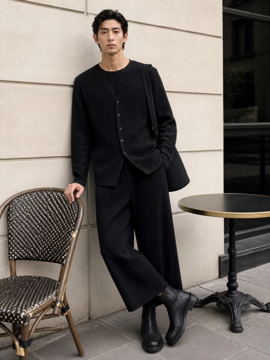 A fully pleated Homme Plissé set in deep black turns quiet texture into the main event, layered from longline knit to cropped wide-leg trouser and matching bucket bag. Bottega’s sculptural slip-on boots add weight and depth at the ankle, keeping the proportions grounded and the monochrome line uninterrupted. The result is a calm, architectural city uniform that reads considered from gallery afternoons to discreet dinners.