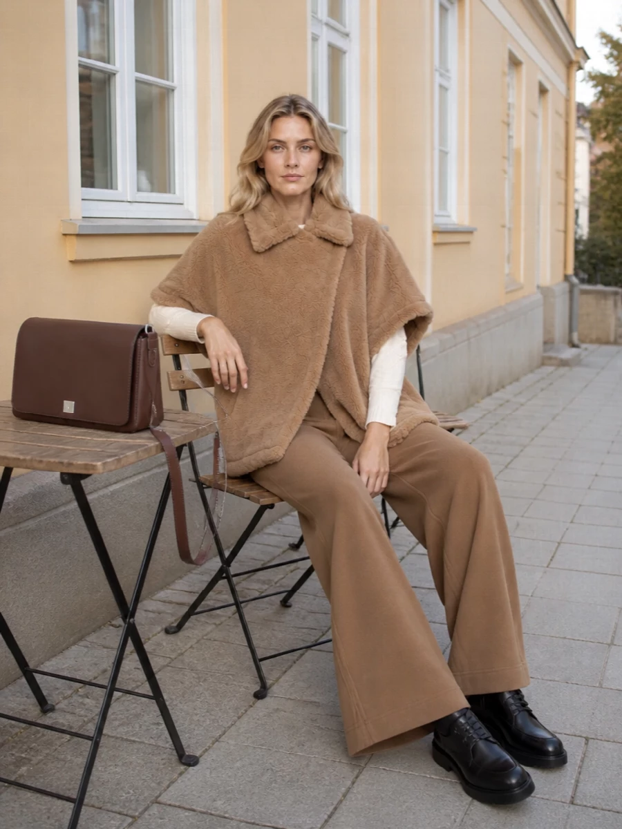 I am deliberately building around the top and trouser path rather than a dress, because the coat’s boxy, short-sleeved shape really needs a clean knit plus wide-leg base to echo the source silhouette. The ivory knit and camel wide-leg create a long, tonal column under the plush coat, while the black derby and chocolate bag sharpen the mood so it feels city-ready rather than purely cozy. The result is quietly luxurious, modern and practical for cold days when you want ease with real polish.
