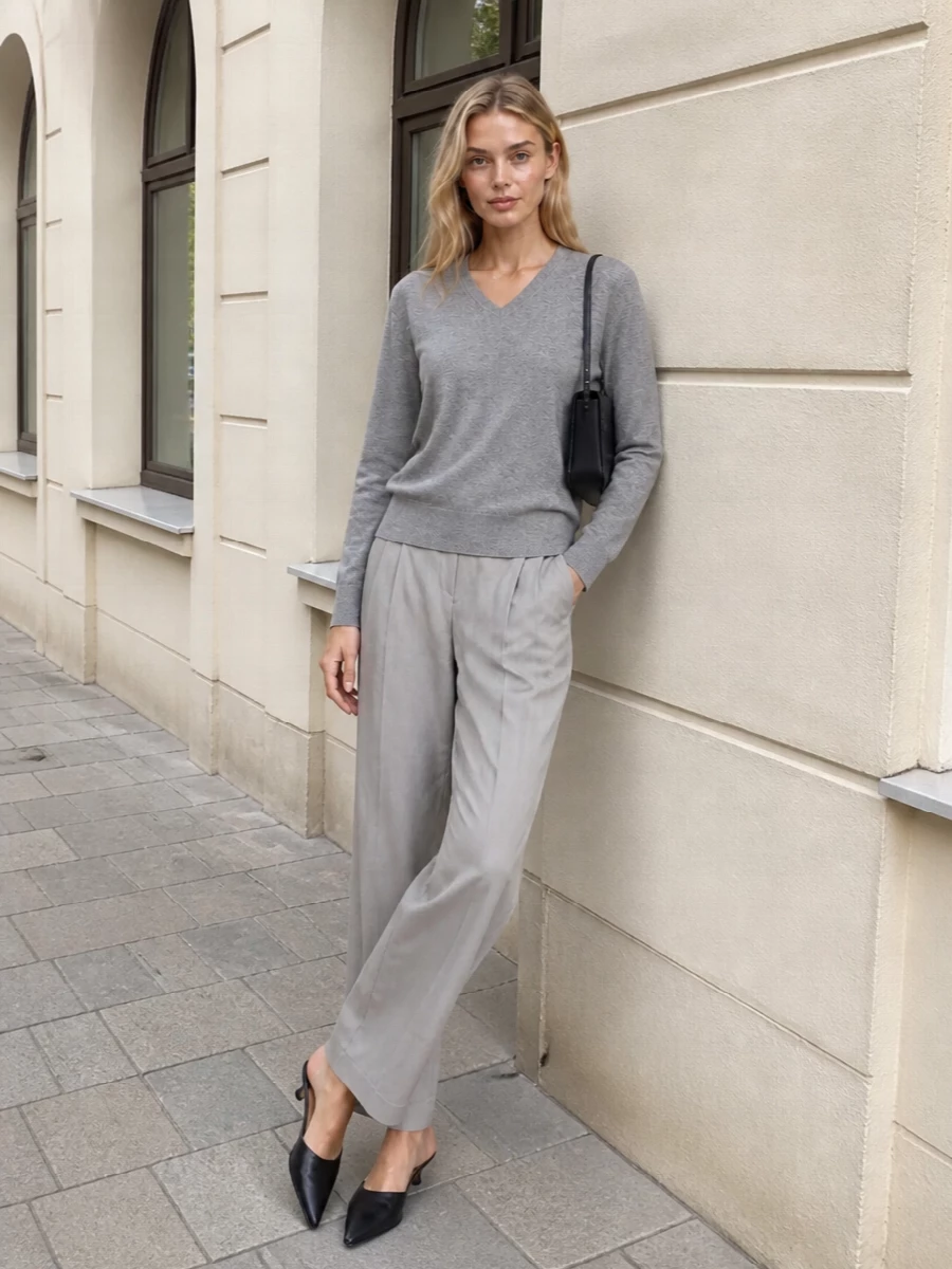 Heather grey and light stone sit quietly together here, giving the knit and tailored trouser a soft, almost monochrome harmony. A pointed black mule and slim black shoulder bag sharpen the lines just enough, keeping the outfit refined without tipping into formality. The result moves easily from daytime meetings to low-key dinners with the same calm, precise energy.
