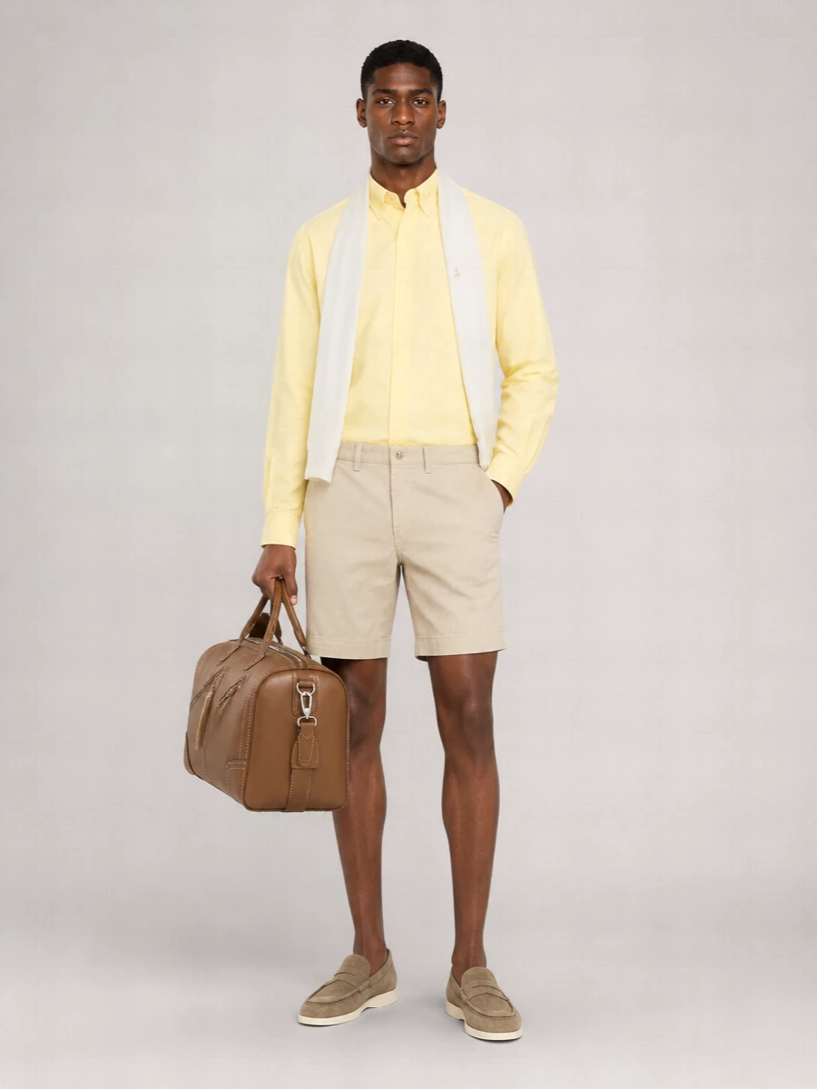 Pastel yellow meets soft stone for a clean, sunlit take on preppy dressing. The chino shorts and suede loafers keep the lines sharp but relaxed, while the tan crossbody and pale scarf add quiet texture and warmth without crowding the color story.