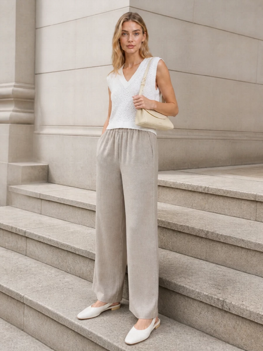 Soft white and light taupe play together in a restrained, tonal pairing that feels calm and precise. The relaxed knit shell and fluid wide-leg trouser create an elongated, easy column, grounded by a sharp flat slingback. A slim buttercream shoulder bag keeps everything intentional and quietly polished for warm-day city dressing or understated lunches.