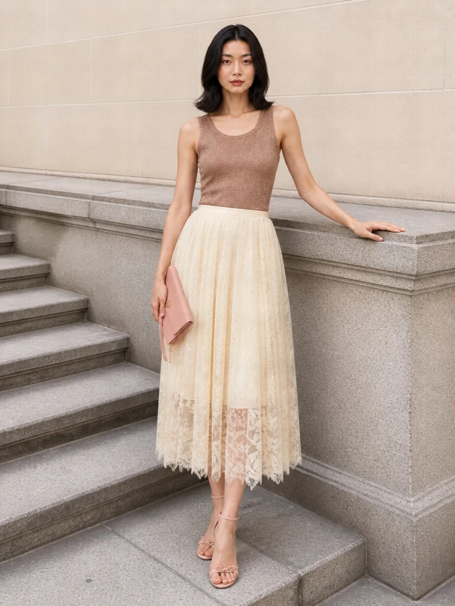 A rose-bronze shimmer tank pairs with a buttercream lace midi skirt for a soft, light-catching column of neutrals. Blush-nude stilettos and a dusty-rose clutch keep the palette whisper-quiet, adding just enough height and polish. A blush wrap at the shoulders finishes the mood with romantic ease that still feels modern and restrained.