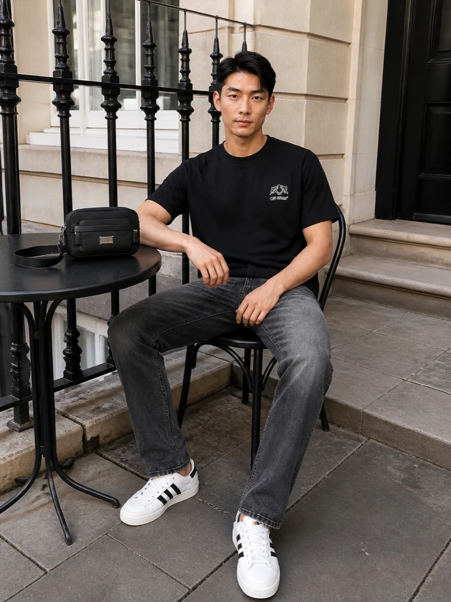 A black Off-White tee and charcoal-faded straight jeans set up a clean, low-key base that feels modern but not try-hard. White Adidas court sneakers with black stripes bring a subtle preppy twist and a hit of contrast, while a compact Emporio Armani crossbody keeps everything hands free and quietly put together. It is an easy city uniform that reads graphic, streamlined and ready for all-day wear.