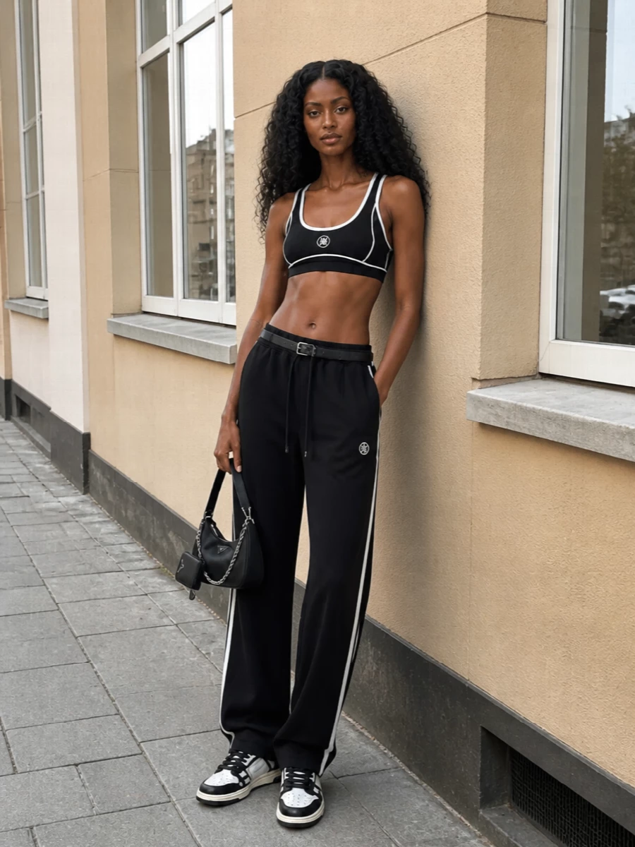 A tight black and white story keeps this Amiri track pant grounded in a true sport-set energy, with the matching bra and court sneakers reading as intentional rather than gym kit. The Prada belt and crescent bag bring just enough structure and hardware to feel city ready, without diluting the relaxed, slouchy silhouette. It is the kind of off-duty uniform that moves easily from airport to late coffee without needing a change of pace.