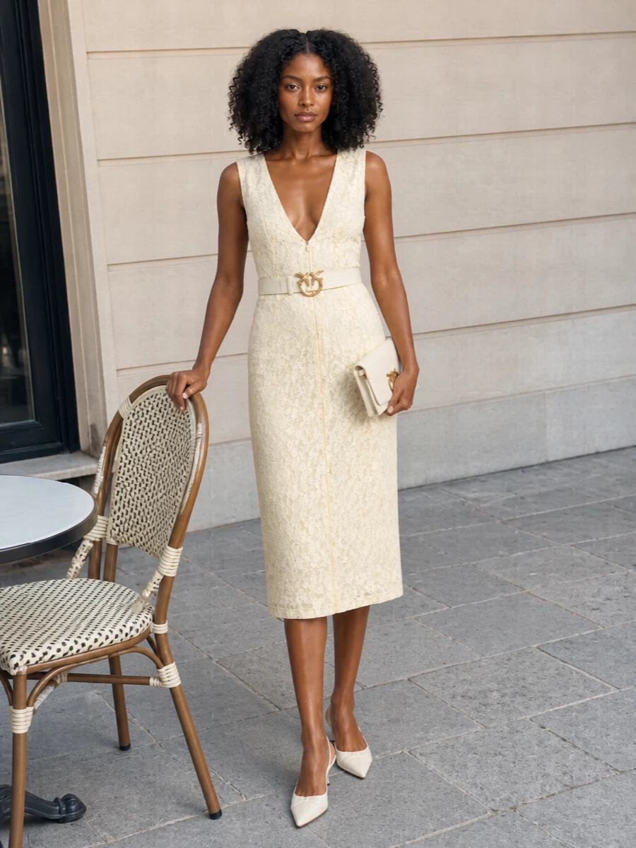 An ivory lace sheath meets equally soft-toned accessories for a quietly romantic cocktail ensemble. Kitten-heel slingbacks and a slim clutch keep the line elongated and light, while a sculpted ivory belt adds just enough definition and gold detail. The result is sensual and polished without ever feeling over-styled, ideal for summer weddings or terrace dinners.