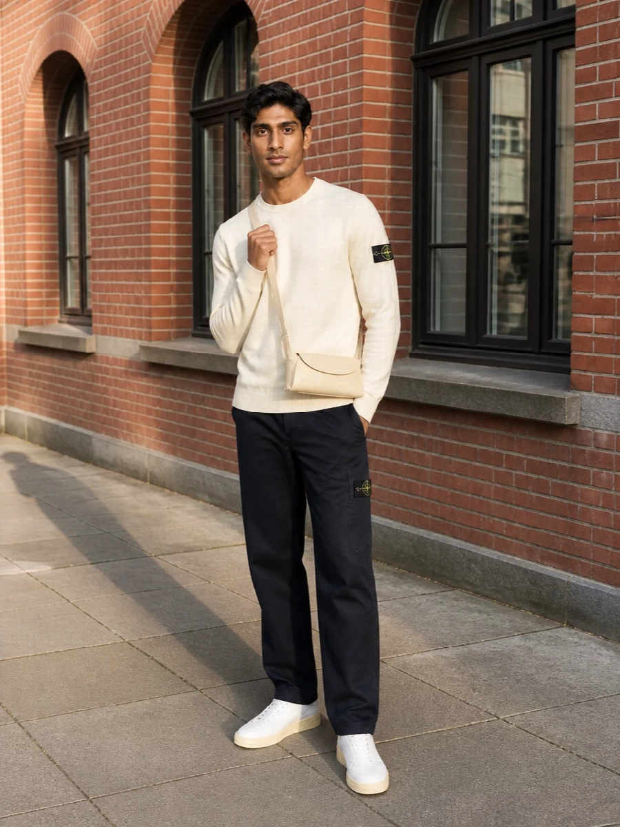 A butter cream Stone Island knit sits over deep navy straight trousers for a clean, street-informed base in quietly technical fabrics. Butter-toned Jil Sander sneakers and a slim matching shoulder bag pull the palette together, keeping the whole outfit precise and minimal while still relaxed enough for everyday city wear.