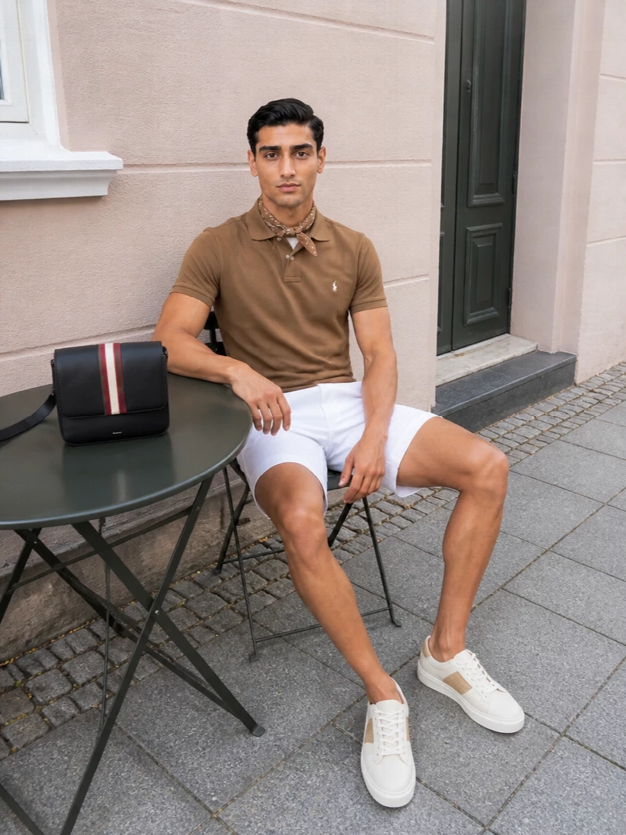 Caramel piqué against crisp white chino shorts feels very East Coast summer, relaxed but still considered. Off-white court sneakers and a structured crossbody keep it firmly in smart-weekend territory rather than pure resort. The camel bandana adds a small nod to Americana that matches the warm tones without competing with the clean lines.