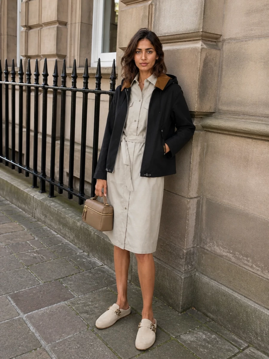 I’m building around the dress path so the Barbour parka can stay the hero outer layer, with the shirt dress giving one clean column underneath instead of breaking the line with separate top and shorts. The stone-beige A.P.C. dress and tan-accented clogs echo the parka’s collar and hardware, while the structured taupe crossbody keeps everything grounded in a practical, city-ready palette. The result is an easy, modern take on city-countryside utility that feels intentional rather than over-styled.