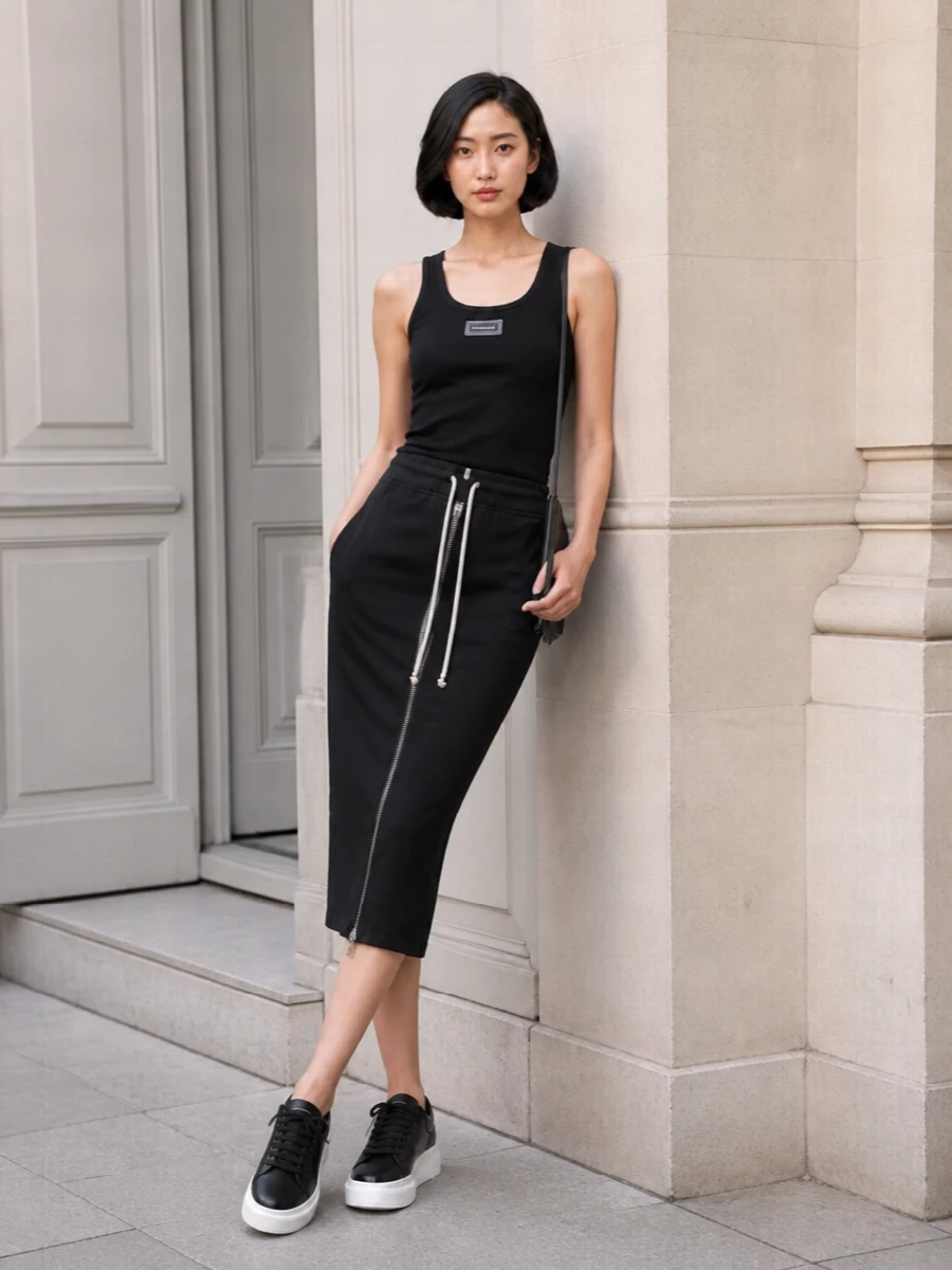Monochrome and graphic, this outfit leans into the skirt’s technical zip and drawcord with a clean logo tank and sculptural platform sneakers. The result is a sleek, utilitarian city uniform that feels considered but easy to move in. A slim black cross-body keeps you hands-free and streamlined from gallery visits to late-night walks home.