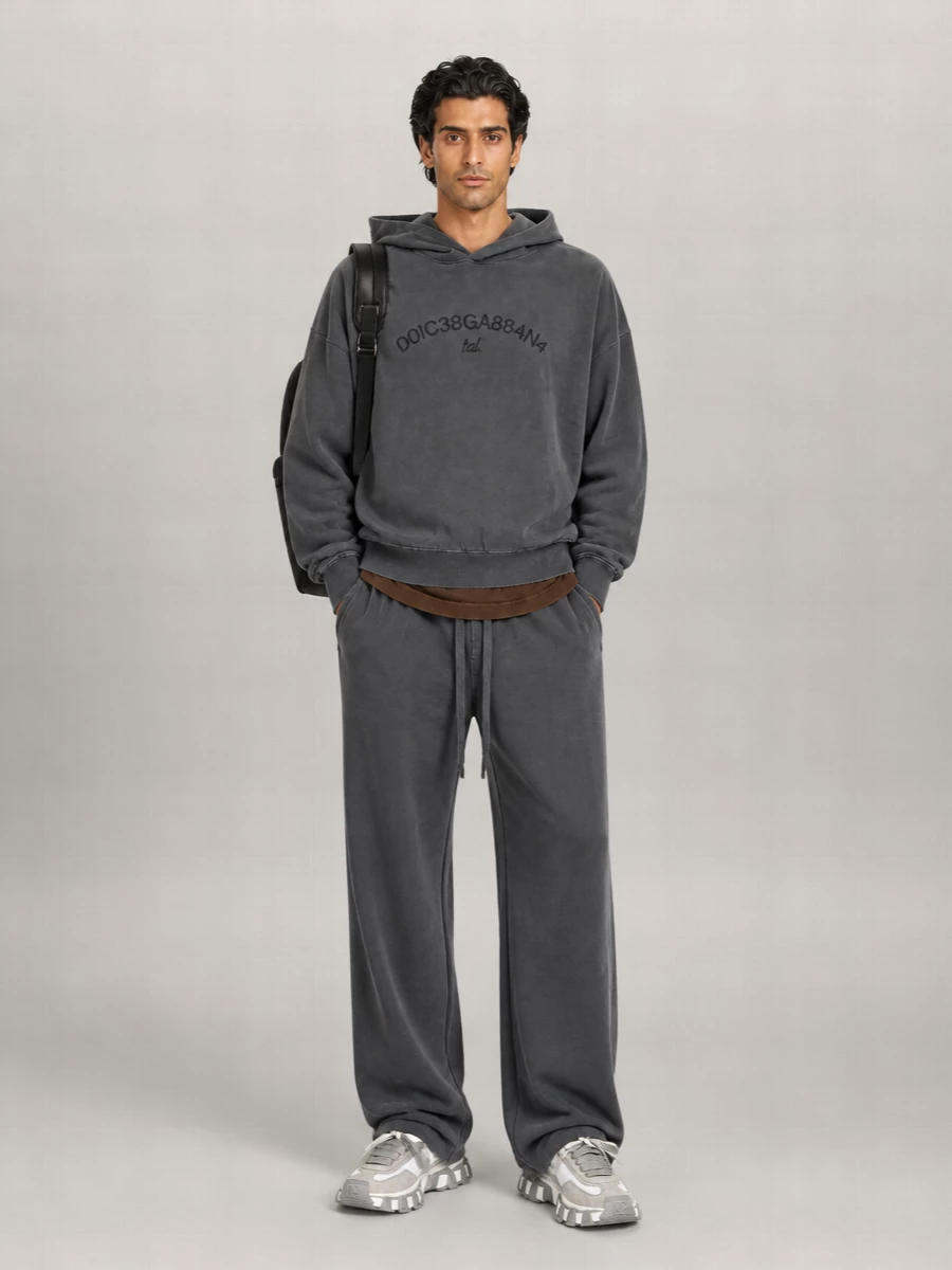 Washed charcoal on charcoal keeps the hoodie and wide-leg pant reading like a considered set, all relaxed volume with a soft, sun-faded mood. Chunky white and grey runners sharpen the base just enough, while the clean black backpack and off-white socks keep the story in a tight, modern street palette. It is an easy city uniform for days when you want comfort to feel quietly dialed-in.
