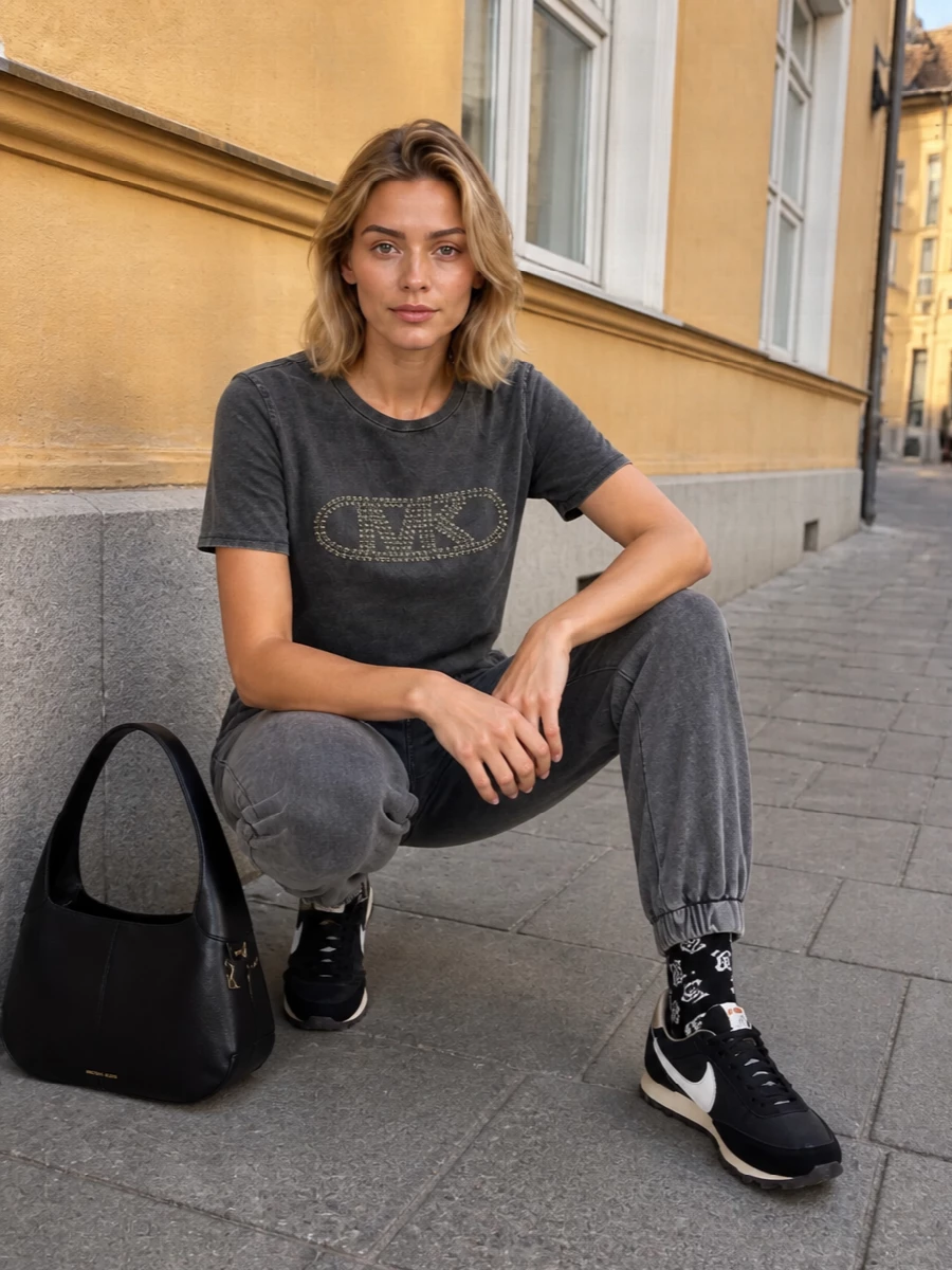 Washed charcoal on top and bottom creates a tight, monochrome base that lets the studded logo feel bold without being loud. Slim black runners and a structured MK shoulder bag sharpen the relaxed jogger silhouette, so the outfit reads city ready rather than gym bound. Printed ankle socks add a small hit of attitude that still sits comfortably inside the clean, sport-led story.