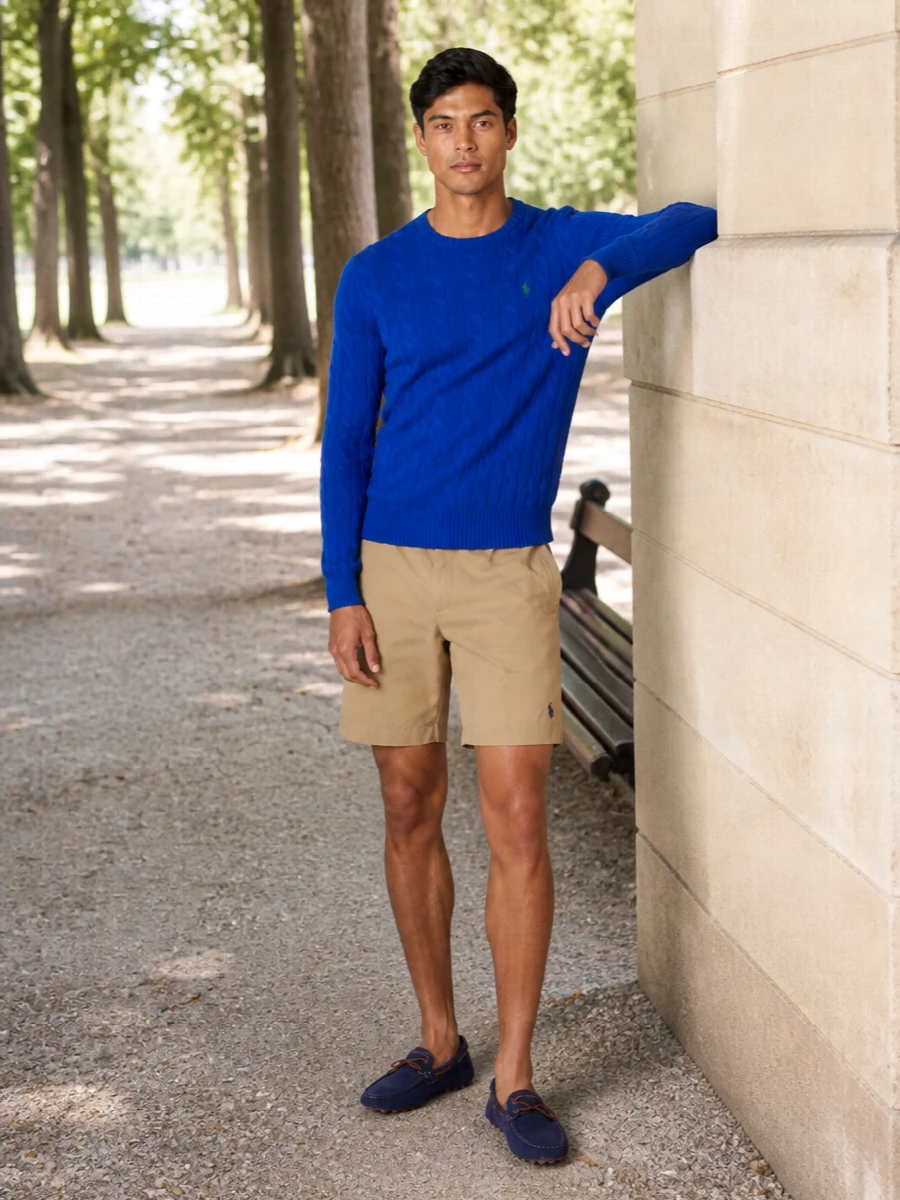 Royal blue cable knit, tailored khaki shorts and navy suede drivers create a clean, collegiate summer outfit that feels relaxed but considered. The proportions stay classic and regular, so the colour and texture do the work, while the structured canvas tote adds a subtle Riviera note that still reads preppy rather than beachy. It is an easy city weekend or terrace-dinner combination that signals polish without dressing up too far.