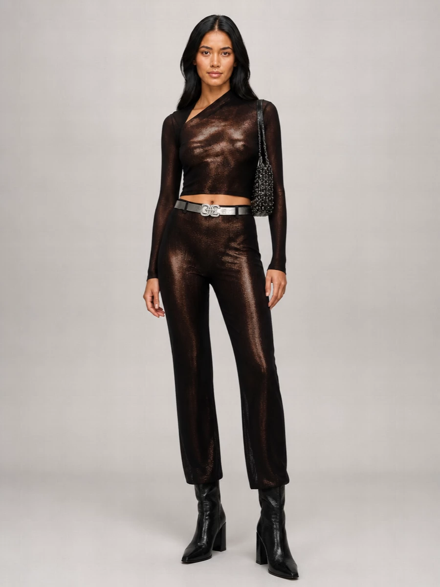 Head-to-toe liquid metallic Gaultier energy, anchored by a razor-slim sheer crop and those high-waisted bronze-black trousers for a long, uninterrupted line. Glossy black knee boots and a chainmail shoulder bag push the club mood into futuristic territory, while the mirrored belt quietly snatches the waist so the sheerness reads intentional rather than bare. It is a confident, nightlife-ready set that feels sculpted, graphic and undeniably fashion-insider.