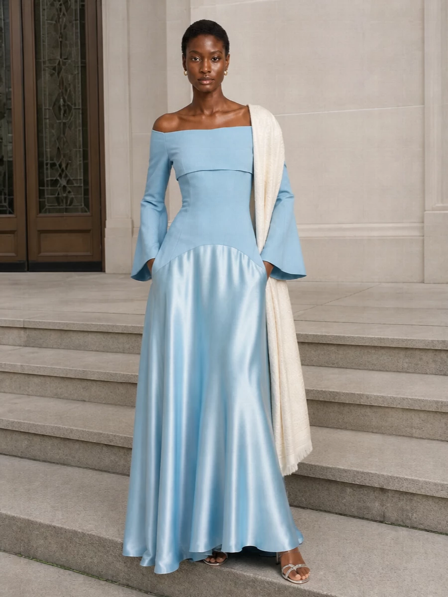 Soft blue satin, mirrored silver and ivory accents create a calm, ultra-refined evening story around the sculpted off-shoulder dress. A barely-there metallic sandal and structured ivory clutch keep the lines long and clean, while a single gold huggie and a whisper of paisley at the shoulder add just enough texture and polish for modern black-tie moments.