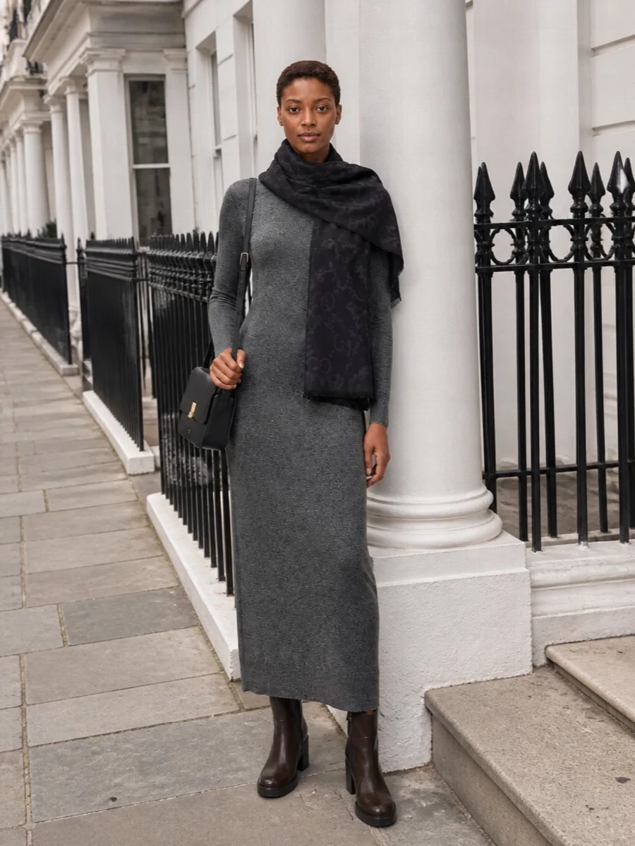 I’m taking the dress route here, letting the Givenchy charcoal knit column act as a quiet stage for the deep Gucci scarf rather than breaking the line with separate top and trouser. The long, clean silhouette, grounded by dark leather ankle boots and a slim black shoulder bag, feels precise but not fussy, ideal for winter days that move easily into dinner. It is all about depth in greys and blacks, subtle texture and a single, confident logo moment at the neck or draped over the shoulders.