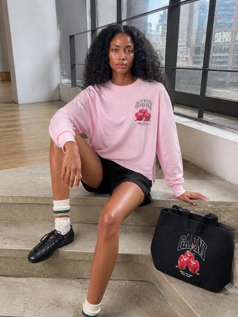 Soft pink, cherry red and inky black come together here in a relaxed, collegiate-feeling mix that feels playful without tipping into costume. The slouchy sweatshirt and easy shorts keep it firmly in off-duty territory, while the lace-up flats and graphic tote give just enough structure and intention for city days. It is the kind of outfit you throw on for coffee, errands or a casual brunch when you still want the palette to feel thought through.