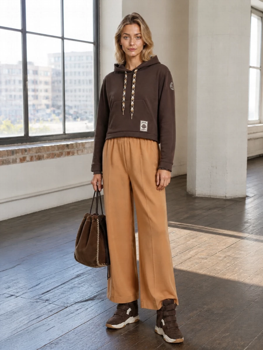 Cropped Moncler jersey and fluid Dries caramel trousers pick up every shade in the Isabel Marant sneakers, from deep chocolate to soft tan. The wide leg and hidden wedge balance each other so you get easy volume on the bottom with a lightly defined waist up top. A tactile Prada suede bucket finishes it with a crafted, boho touch that still reads quietly luxurious for city days.