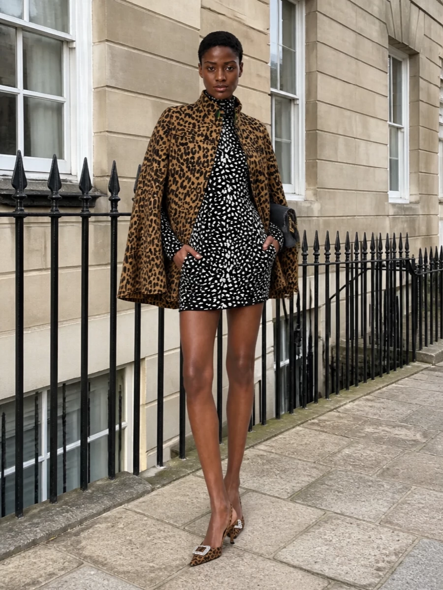 I’m taking the dress route here, pairing the Valentino leopard cape with a sculpted Cavalli animal-print mini for a controlled, high-impact statement that still reads polished. Strong black accessories keep all the pattern intentional rather than chaotic, giving you a feline, nightlife-ready ensemble that feels editor-approved not costume. The result is pure winter party energy: bold cape, sharp mini, and a clean black-gold frame around all that leopard.