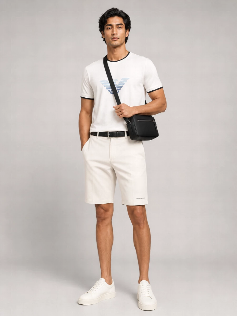 Emporio Armani’s light bermuda shorts set an easy, refined base, paired with the tipped white tee for a crisp mix of sport and quiet branding. Creamy off-white sneakers keep the line streamlined and cohesive, while the black crossbody and matching belt add just enough structure for city days without disturbing the relaxed mood. The result is a clean, warm-weather outfit that moves effortlessly from daytime errands to casual dinners.