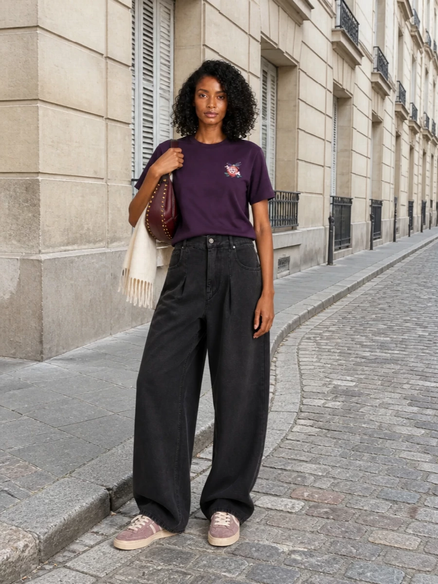 Casual but considered, this pairing lets the plum tee sit against slouchy charcoal tailoring for a relaxed, slightly androgynous line. Mauve sneakers and a burgundy crescent bag keep everything tonal and graphic, with an ecru scarf softening the palette for cooler days. It is an easy city uniform that still feels quietly intentional from coffee runs to low-key dinners.
