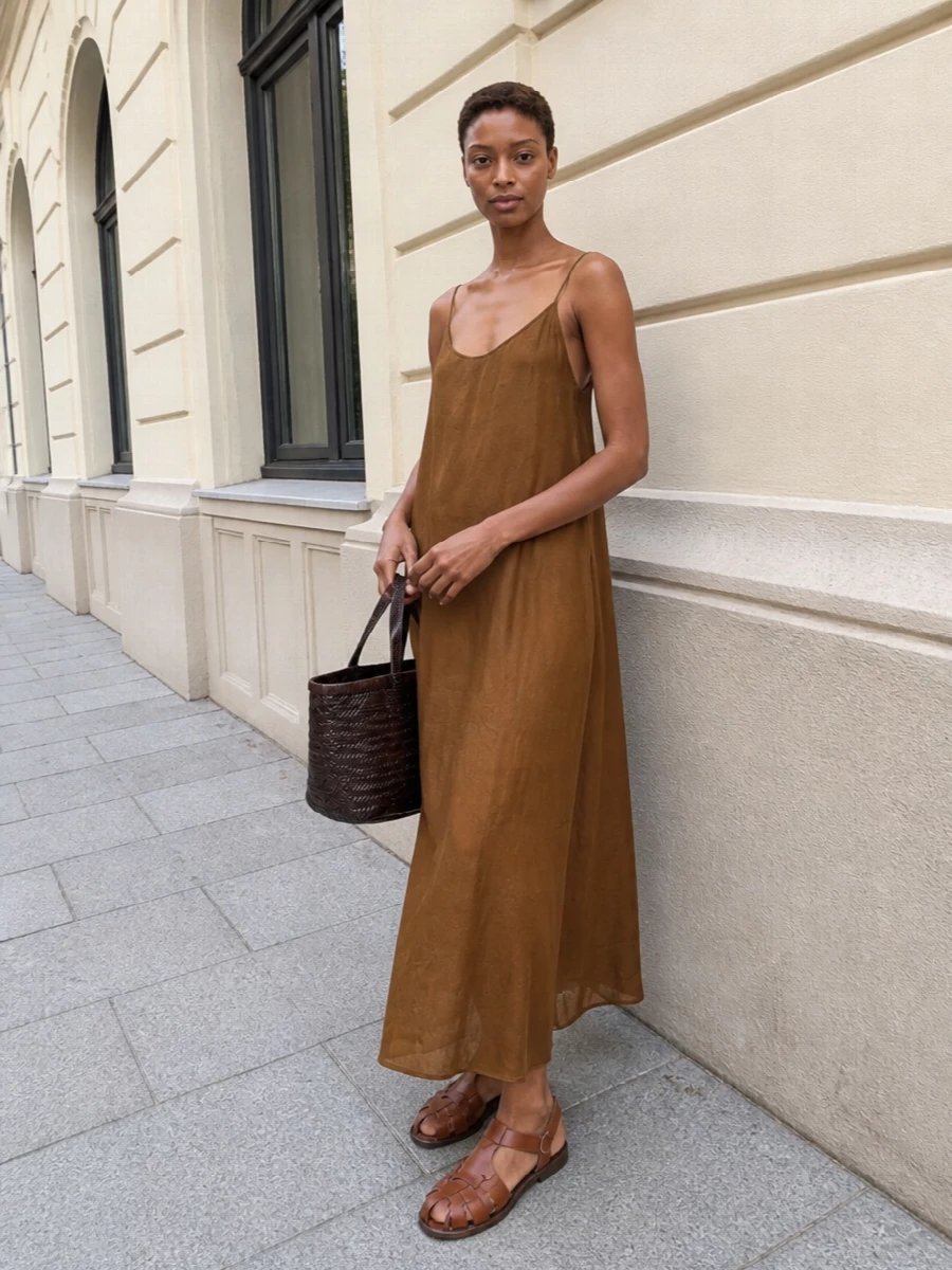 I anchored the outfit with the Uma Wang caramel slip dress rather than separates so the silhouette feels long, fluid and easy against the structured basket tote. The warm brown column and tan fisherman sandals play into a Mediterranean boho story, with texture coming from leather and weave instead of print. Together it reads as relaxed resort city dressing that moves from market mornings to sunset drinks with just a change of jewellery or lip colour.