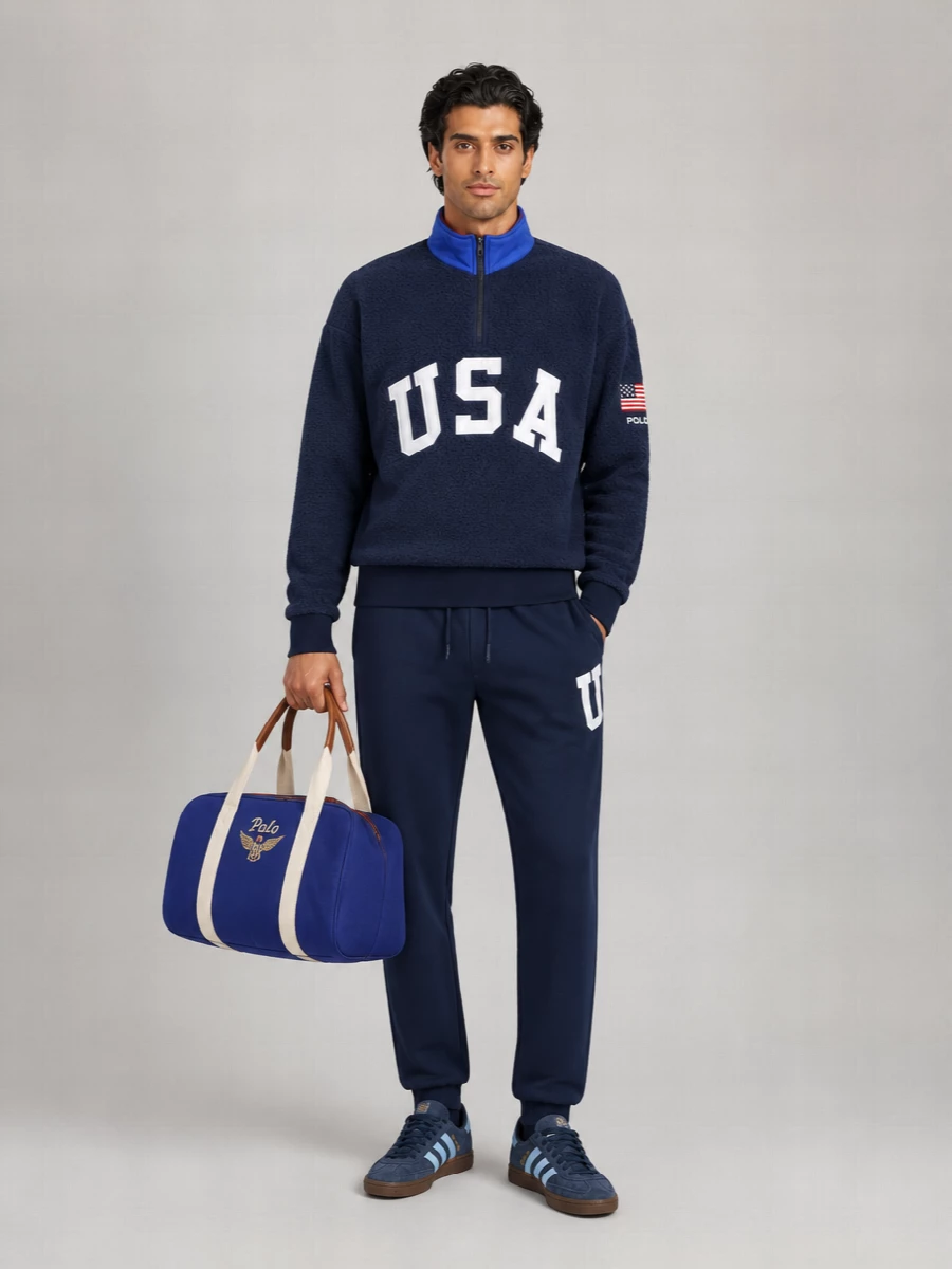 A head‑to‑toe Polo Ralph Lauren sport prep story, this outfit doubles down on navy and varsity USA graphics for a strong, cohesive statement. The tapered track pants and terrace sneakers keep the silhouette clean and athletic, while the royal‑blue duffle underlines the collegiate, on‑the‑move energy. It is built for cool city days, stadium runs, or casual travel where comfort and bold Americana branding are the point.