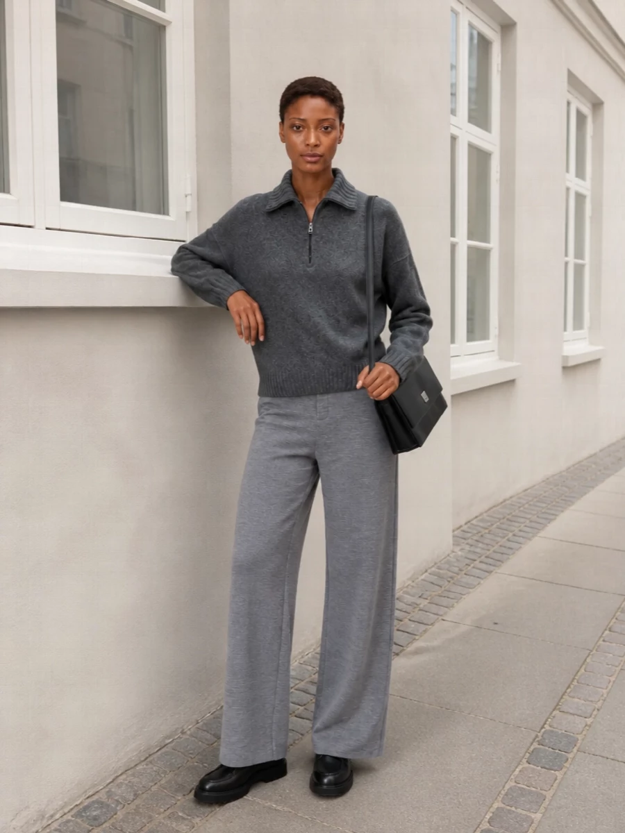 A column of greys keeps the half zip firmly in minimalist territory, with heather wide-leg trousers echoing its softness but reading a touch more tailored. Chunky black derbies and a sharp black cross-body add structure and definition, keeping the knit-on-knit pairing city-ready rather than lounge. The result is quietly relaxed yet intentional, ideal for workdays that blend into slow evenings out.