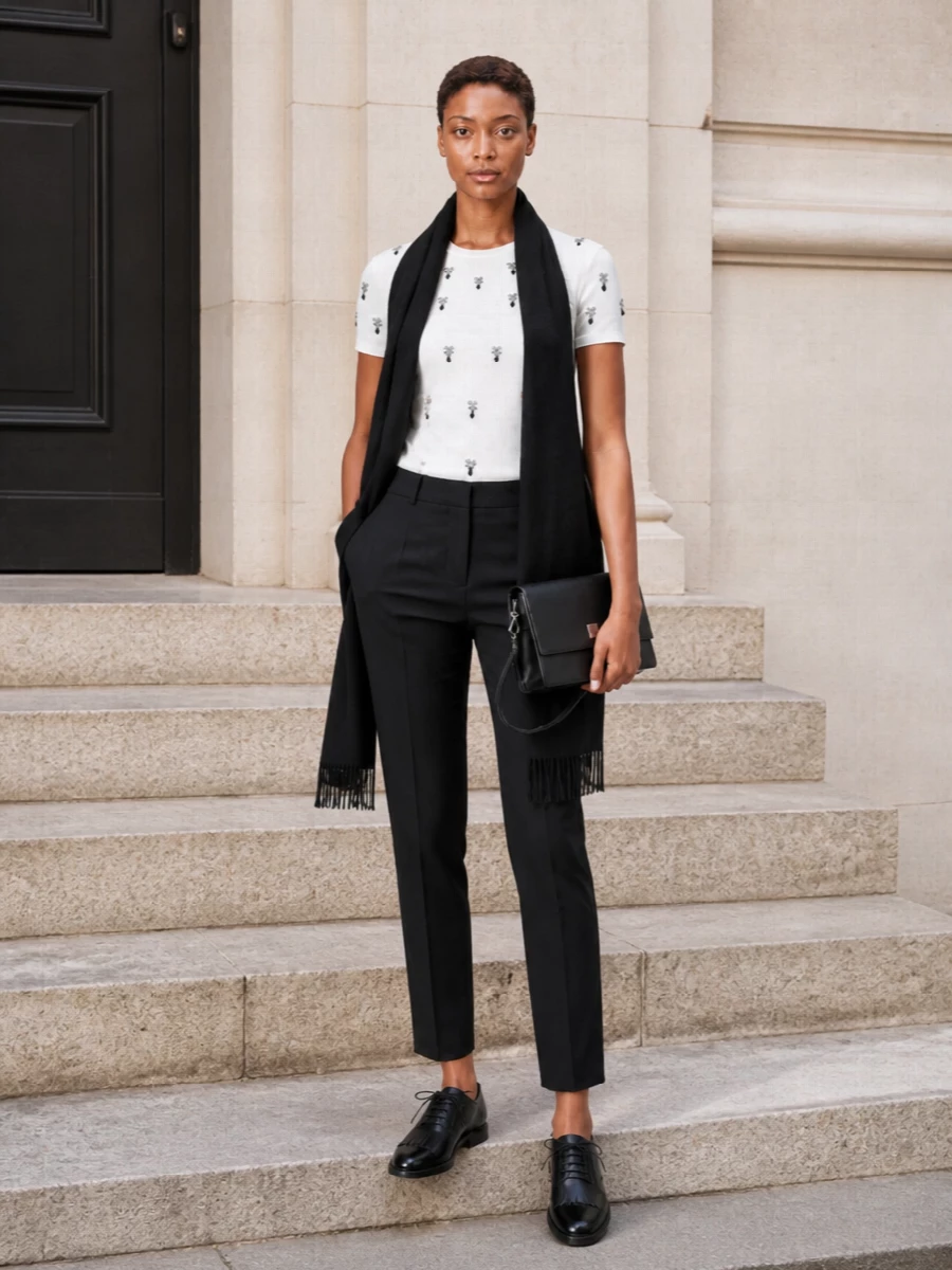 The embellished S Max Mara tee is sharpened with clean black tailored trousers for a precise, monochrome column that feels polished without effort. Black derbies and a structured crossbody keep the mood modern and minimal, letting the subtle sparkle stand out. A long black scarf adds winter softness while staying firmly in the quiet luxury space.