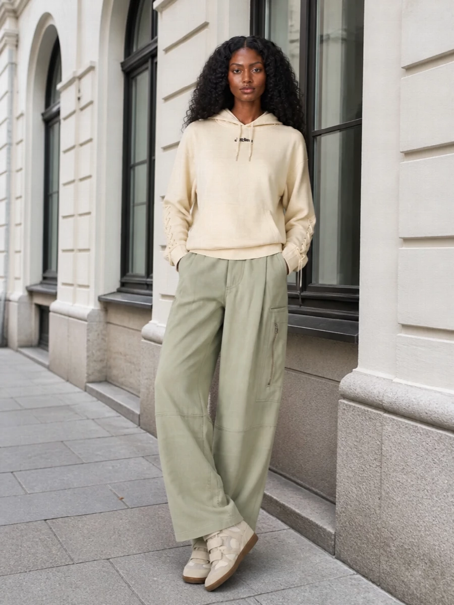 This is a neutral, sport-inflected city uniform built around soft volume and clean utility. The longline hoodie and high-waisted cargos play with scale to complement the wedge sneakers, while tonal beiges and sage keep everything cohesive. I chose the top-and-bottom route rather than a dress so the sneakers feel intentional and athletic, not like an afterthought to tailoring or occasionwear.