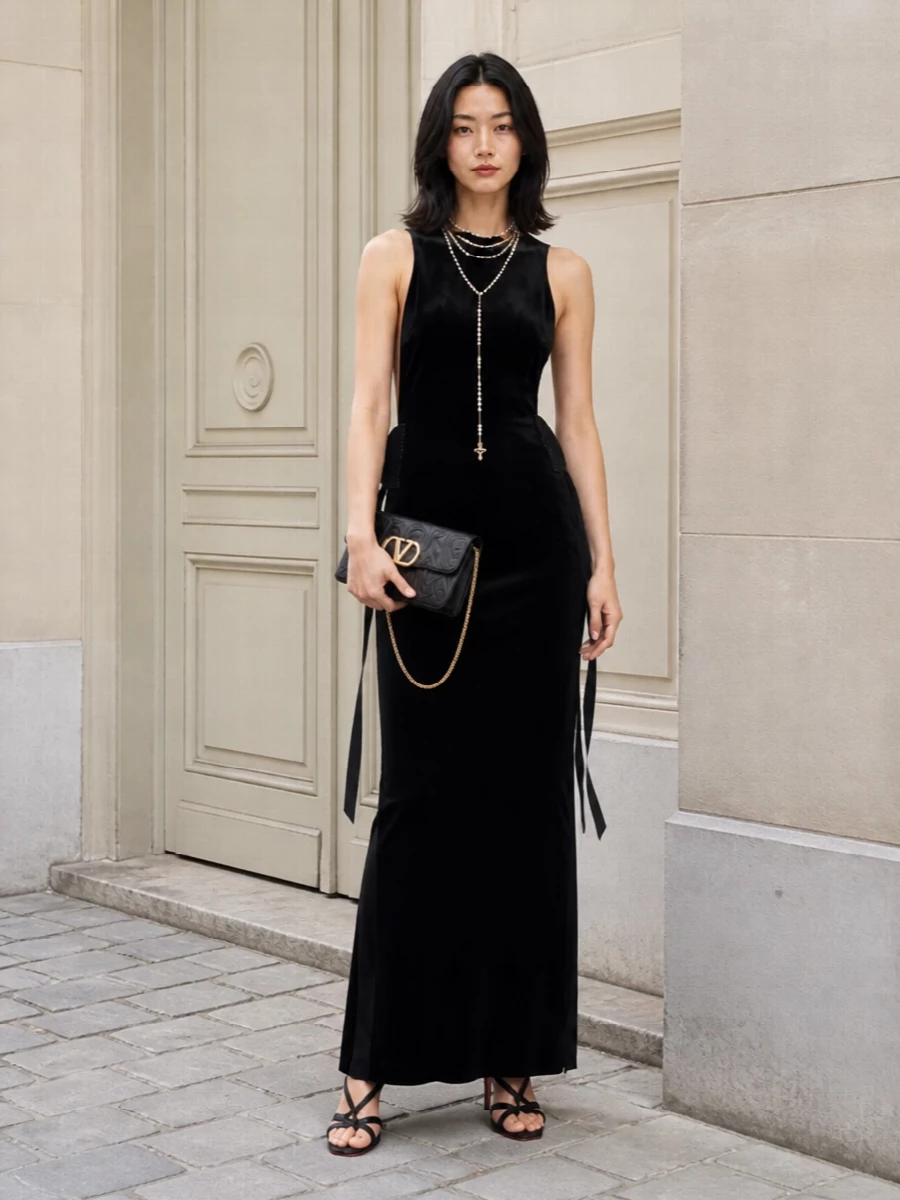 An inky velvet column anchors the outfit, its sculpted simplicity contrasted with a single, fluid cascade of pearls at the neck. Strappy black stilettos and a compact Valentino mini bag keep everything sharply refined, so the drama comes from line and texture rather than overt sparkle. The result is romantic, cinematic evening dressing that feels rich, modern and quietly commanding.