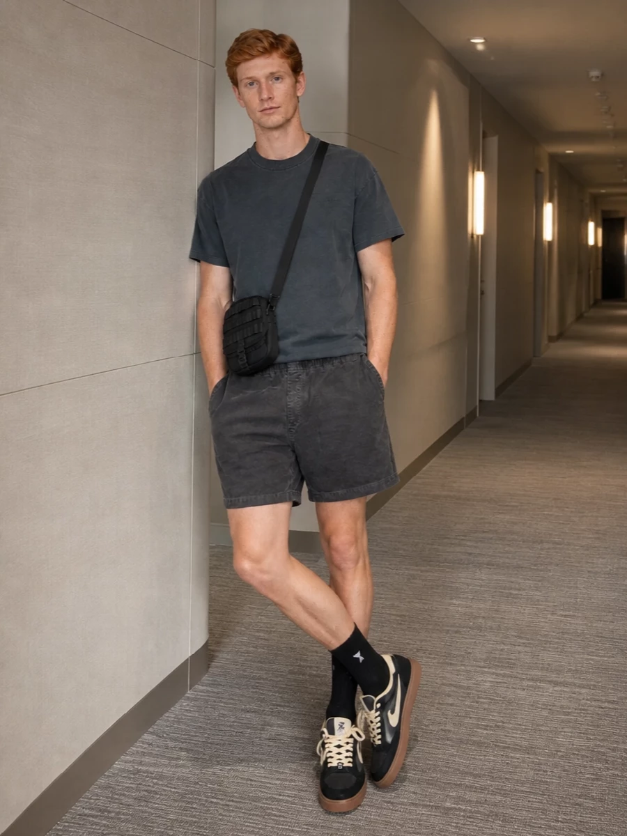 A washed charcoal tee with matching cord shorts keeps everything tonal and easy, letting texture do the work. Off-White skate sneakers and black ribbed socks sharpen it just enough, still reading relaxed and city-ready. The compact Carhartt crossbody adds functional detail without breaking the clean, utilitarian mood.