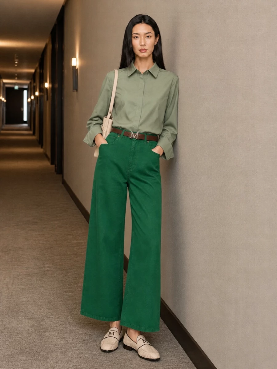 A tonal play on green that feels calm but assured, pairing the deep wide-leg trouser with a crisp sage shirt for a clean, elongated line. Woven loafers and a buttercream shoulder bag introduce soft texture and lightness, while a slim brown belt quietly anchors the waist and ties the neutrals together. The result reads like relaxed tailoring that can move from studio days to understated dinners without changing a piece.