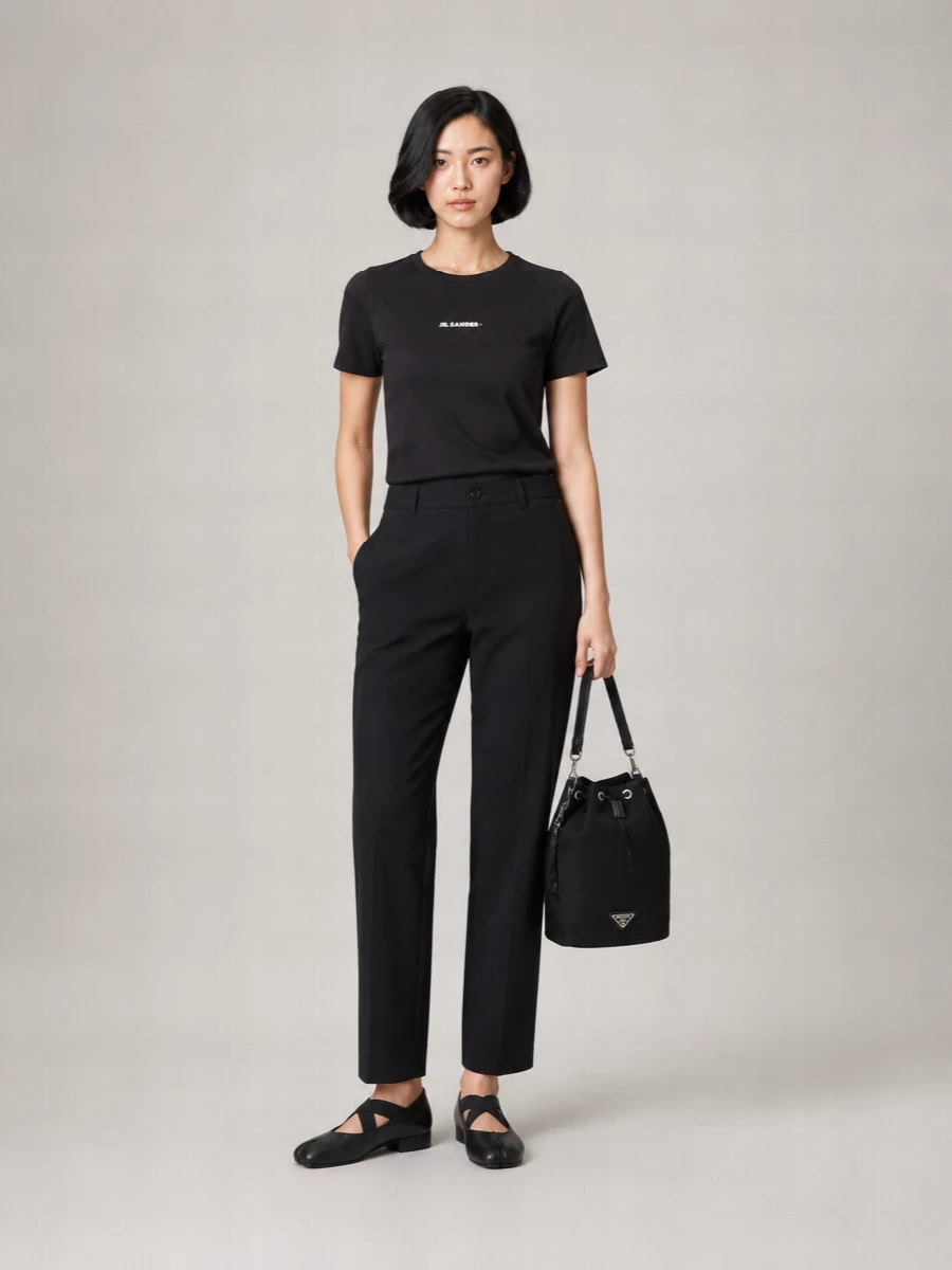A black-on-black base lets the Prada bucket bag read as a considered object rather than an accessory afterthought. The Jil Sander tee and Marni trouser create a clean, columnar line, while the sculptural Uma Wang flats keep the mood calm and quietly precise. This path beats the dresses here by staying closer to the bag’s everyday urban brief and making the whole outfit genuinely work from errands to an understated dinner.