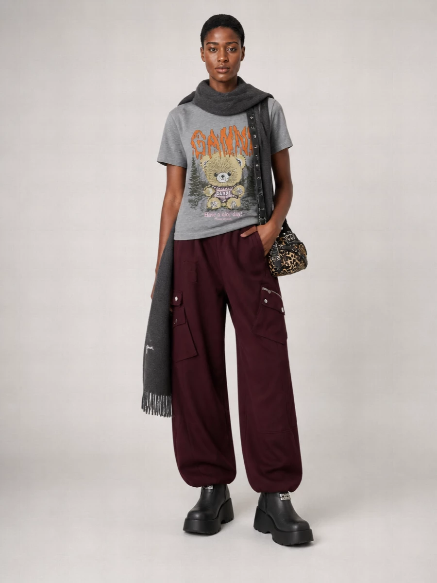 Heather-grey graphics meet deep burgundy cargos for a slouchy, city-ready mix that feels playful but not try-hard. Chunky black platforms keep the proportions grounded, while the mini leopard cross-body delivers a sharp little jolt of pattern. The palette stays moody and cohesive so the bear tee has all the space to be the punchline.